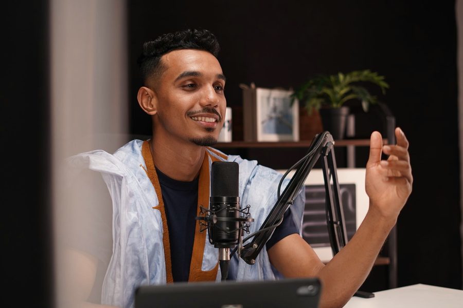 A creator mid sentence at a studio microphone in a home setup