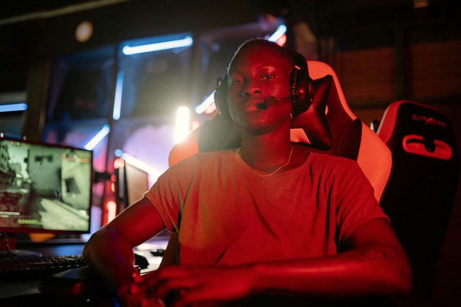 A gamer with a headset at a lit gaming setup